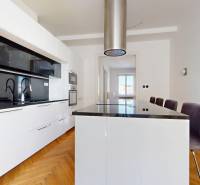Küche in einer 3-Zimmer-Wohnung mit einer schwarzen Kücheninsel und weißen Schränken.