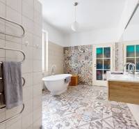 Badezimmer in einer 3-Zimmer-Wohnung mit bunten Fliesen, Badewanne und Doppelwaschbecken.