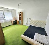 Ein Zimmer in einer 3-Zimmer-Wohnung mit einem Bett, einem Tisch und einem grünen Teppich.