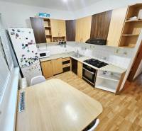 Küche in einer 3-Zimmer-Wohnung mit Herd, Kühlschrank und Holztisch.