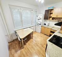 Küche mit Herd, Kühlschrank und Tisch in einer 3-Zimmer-Wohnung.