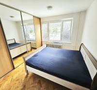 Schlafzimmer in einer 3-Zimmer-Wohnung mit Holzboden, großem Schrank und Bett.
