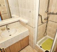 Badezimmer mit Waschbecken, Duschkabine und Fliesen in einer 3-Zimmer-Wohnung.