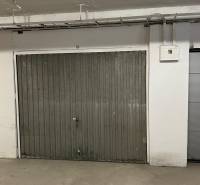 Metalltür in der Garage mit Rohrleitungen und einem Elektroschaltkasten an der Wand.