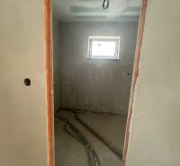 Unvollendetes Zimmer in einem Einfamilienhaus mit Fenster und vorbereiteter Elektroinstallation.