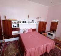 Schlafzimmer mit Holzmöbeln und rosa Bettwäsche in einem Einfamilienhaus.