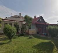 Ein Einfamilienhaus in Hrkovce mit Garten, Sträuchern und einem Holzunterstand.