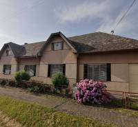Ein Einfamilienhaus in Hrkovce mit Blumen vor dem Zaun und einem Schrägdach.