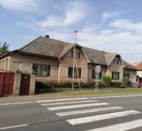 Ein Einfamilienhaus in Hrkovce an der Straße, mit Ziegeldach, geschlossene rote Tore.