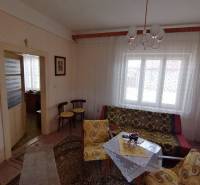 Wohnzimmer in einem Einfamilienhaus mit Retro-Möbeln, gemusterten Vorhängen und sanfter Beleuchtung.