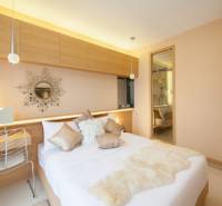 Helles Schlafzimmer in einer 2-Zimmer-Wohnung mit dekorativem Spiegel über dem Bett.