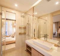 Badezimmer in einer 2-Zimmer-Wohnung mit Duschkabine und Waschbecken, das ins Schlafzimmer führt.