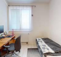 Innenraum eines Einfamilienhauses mit Bett, Schreibtisch und Stuhl am Fenster.