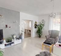 Wohnzimmer in einem Einfamilienhaus mit Sofa, Sessel, Fernseher und Dekorationen an den Wänden.