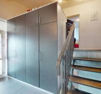 Eingangshalle in einem Einfamilienhaus mit einem großen Schrank, einer Treppe und Glastüren.