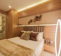 Schlafzimmer in einer 3-Zimmer-Wohnung mit Spiegel, Holzelementen und sanfter Beleuchtung.