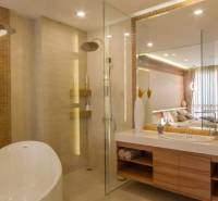Badezimmer in einer 3-Zimmer-Wohnung mit Badewanne, Dusche und großem Spiegel. Elegante Beleuchtung ergänzt den Raum.