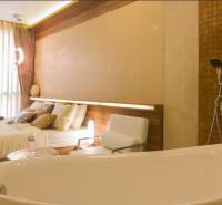 Luxuriöses Schlafzimmer mit Whirlpool in einer 3-Zimmer-Wohnung, harmonische Kombination aus Holz und natürlichen Farbtönen.