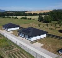 Einfamilienhäuser in Podlužany mit modernen Dächern und Sonnenkollektoren auf dem Feld.