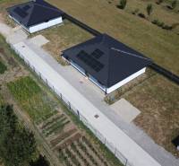 Ein Einfamilienhaus in Podlužany mit Photovoltaikmodulen, einem Garten und umliegenden Feldern.