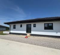 Ein Einfamilienhaus in Podlužany mit Solarpaneelen und einem Schrägdach auf einem Kiesgrundstück.