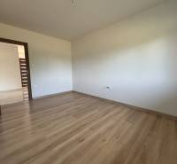 Ein leerer Raum in einem Einfamilienhaus mit Holzboden und weißen Wänden.