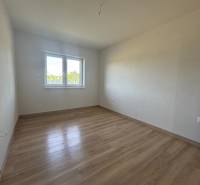 Ein leerer Raum mit Holzboden und einem Fenster in einem Einfamilienhaus.