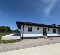 Ein Einfamilienhaus in Podlužany mit einem Rasen-Grundstück und einer Kieszufahrtsstraße.