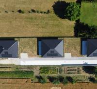 Luftaufnahme von drei Einfamilienhäusern in Podlužany mit Solarpaneelen auf den Dächern.