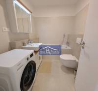 Badezimmer in einer 2-Zimmer-Wohnung mit Waschmaschine, Waschbecken und Badewanne.