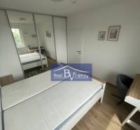 Schlafzimmer in einer Zweizimmerwohnung mit Bett, Kleiderschrank und kleinem Schreibtisch.