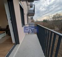 Der Balkon einer 2-Zimmer-Wohnung in der Hraničná-Straße in Bratislava - Ružinov, mit Blick auf die Bäume.
