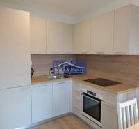 Küche in einer 2-Zimmer-Wohnung mit weißen Möbeln und einer Holzarbeitsplatte.