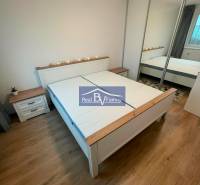 Schlafzimmer in einer 2-Zimmer-Wohnung mit Holzboden, Doppelbett und Einbauschrank.