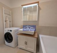 Badezimmer in einer 2-Zimmer-Wohnung mit Waschmaschine, Waschbecken und Badewanne.