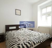 Schlafzimmer mit Bett und Nachttischen in einer 2-Zimmer-Wohnung.
