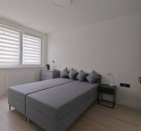 Schlafzimmer in einer Einzimmerwohnung mit Ehebett, Nachttischen und einem Fenster mit Rollläden.
