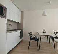 Küchenecke in einer Einzimmerwohnung mit weißen Schränken und Esstisch.