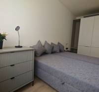 Schlafzimmer mit Doppelbett, Schrank, Kommode und Dekoration in einer Einzimmerwohnung.