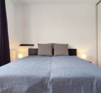 Schlafzimmer in einer 2-Zimmer-Wohnung mit einem großen Bett, Fenster mit dunklen Vorhängen.