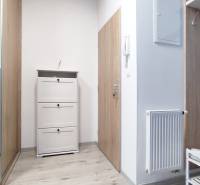 Flur mit weißen Möbeln und Kleiderhaken in einer 2-Zimmer-Wohnung, helle Holzböden.