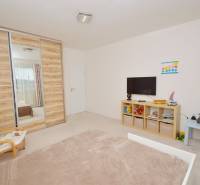 Kinderzimmer in einem Einfamilienhaus mit Einbauschrank, Fernseher und Regalen mit Spielzeug.