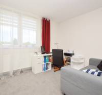 Ein Zimmer in einem Einfamilienhaus mit Sitzgelegenheit, Schreibtisch und roten Vorhängen.