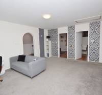 Innenraum eines Einfamilienhauses mit Sessel, Sofa und auffälligen Tapeten an der Wand.