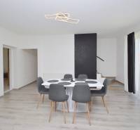 Esstisch mit fünf Stühlen, Uhr und Treppe in einem Einfamilienhaus.