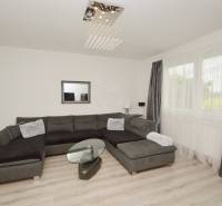 Wohnzimmer in einem Einfamilienhaus mit dunklem Sofa und Glastisch.