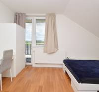 Helles Zimmer in einem Einfamilienhaus mit Bett, Tisch und Schrank.