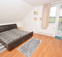 Schlafzimmer im Einfamilienhaus mit Ehebett, Teppichen und großem Fenster.
