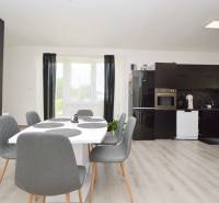 Esszimmer mit Küche in einem Einfamilienhaus mit schwarzen Möbeln und grauen Stühlen.