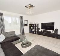 Wohnzimmer mit großer Couch, Glastisch und Fernseher in einem Einfamilienhaus.